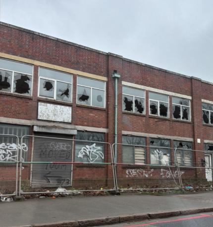 A disused industrial unit with smashed windows and graffiti